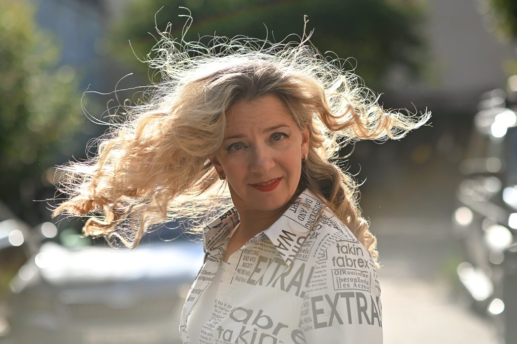 Anna Rikko outdoors in a newspaper-print outfit